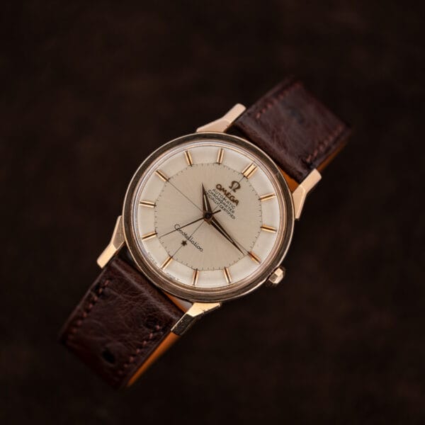 Diagonal front view of Omega Constellation 167.005 showing rose gold capped dogleg lugs against dark fabric