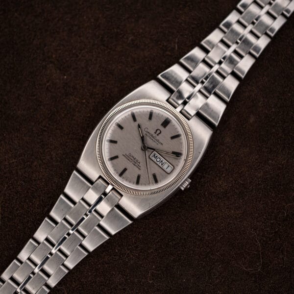 Full Omega Constellation 168.045 laid diagonally with extended integrated stainless steel bracelet on a dark surface