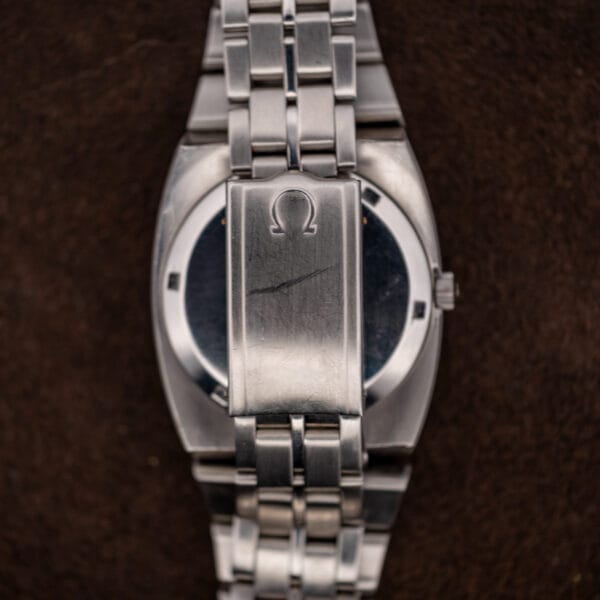Omega Constellation bracelet folded over the caseback, showing the clasp cover and raised Omega emblem