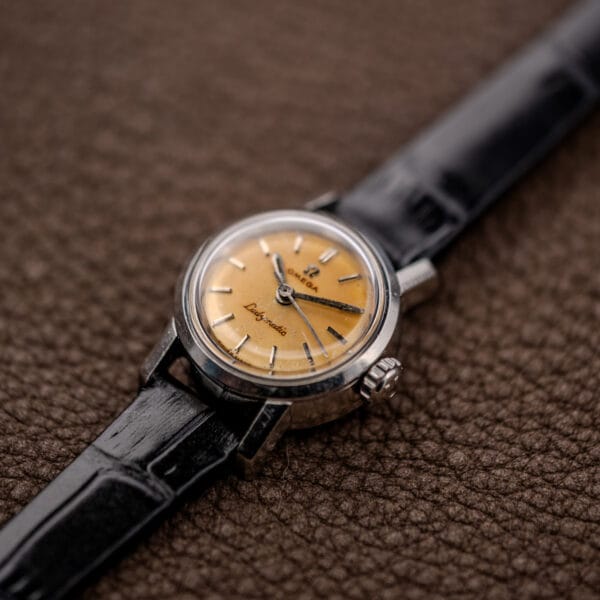 Angled Ladymatic face with domed crystal, smooth bezel, faceted lugs and Omega-signed crown