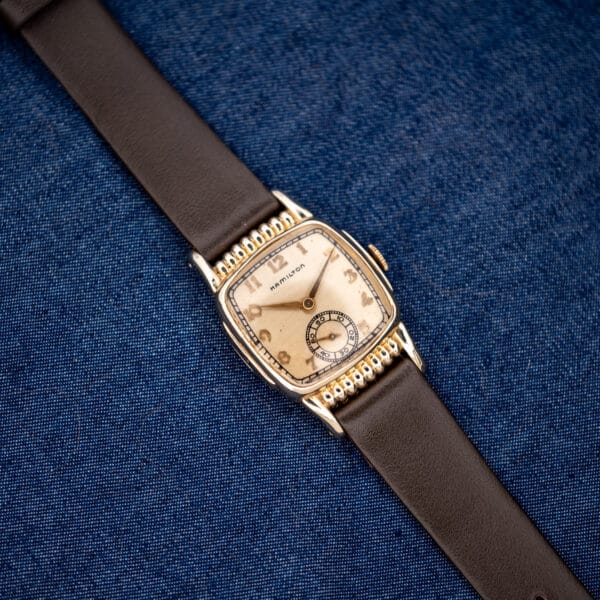 Overhead Hamilton Roland on blue fabric with silver dial, Arabic numerals and brown leather