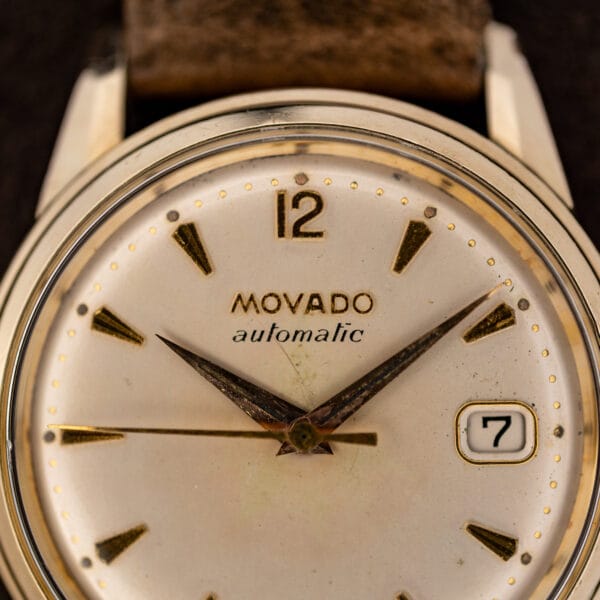 Movado 64389 dial close-up showing applied twelve, dauphine hands and automatic signature