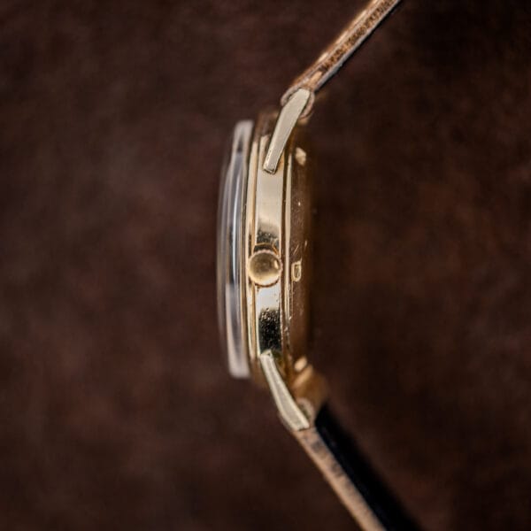 Movado 64389 crown-side profile showing fluted winding crown and curved crystal