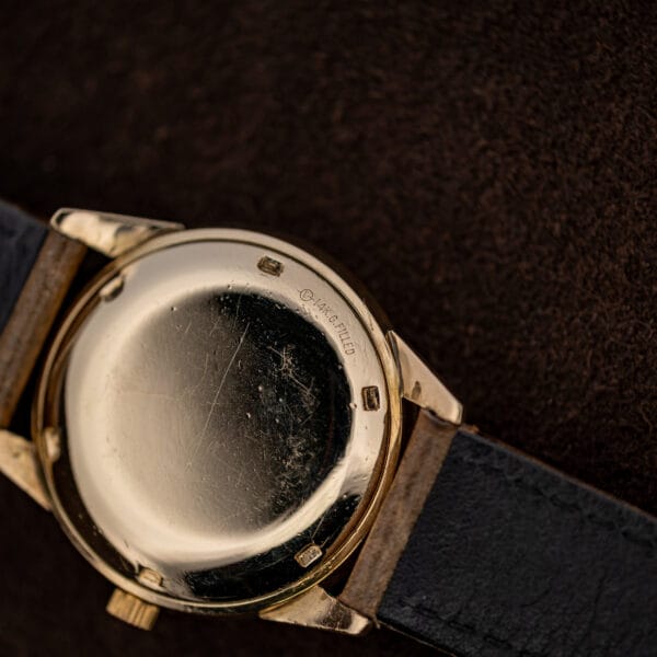 Movado caseback close-up showing the fourteen karat gold-filled inscription near the edge