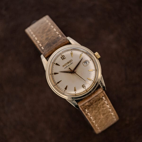 Movado Automatic 64389 on display stand with stitched leather strap looping behind