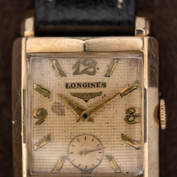 Longines waffle dial close-up showing Arabic numerals, winged hourglass emblem and broad pointed hands