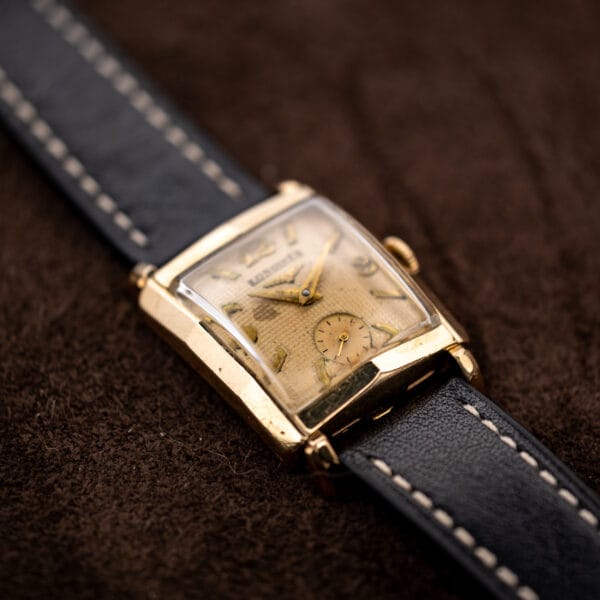 Low angled Longines waffle dial view with round seconds register and contrasting leather strap stitching