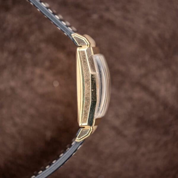 Opposite Longines case profile highlighting curved crystal, geometric lug sides and black leather edges