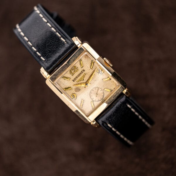 Longines waffle dial and faceted square case displayed on a curved black leather strap