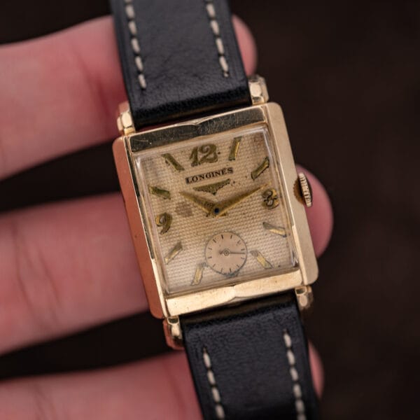 Handheld Longines front view showing waffle texture, winged hourglass emblem and circular small seconds