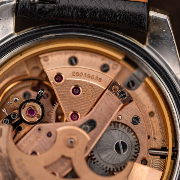 Omega caliber 751 movement close-up showing stamped bridge number, visible jewels and adjacent winding gear