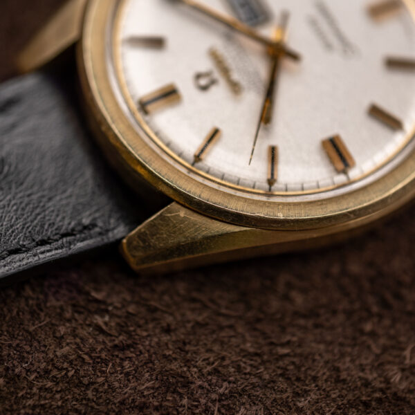 Omega Seamaster lug and bezel close-up showing case contours, crystal edge and adjacent black strap stitching