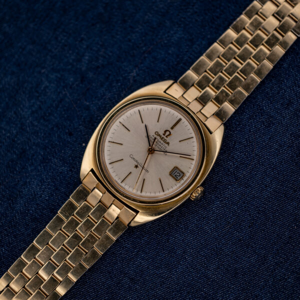 Omega Constellation 168.017 and articulated bracelet arranged diagonally across textured navy fabric