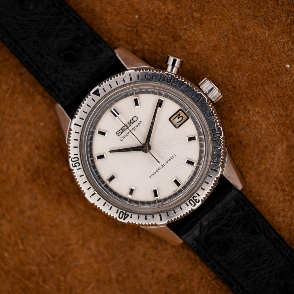 Seiko 5717-8990 mono-pusher chronograph at a diagonal, showing the white dial, timing bezel, date window and black strap