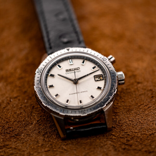Seiko 5717-8990 mono-pusher chronograph displayed on a stand with its timing bezel and black ostrich strap