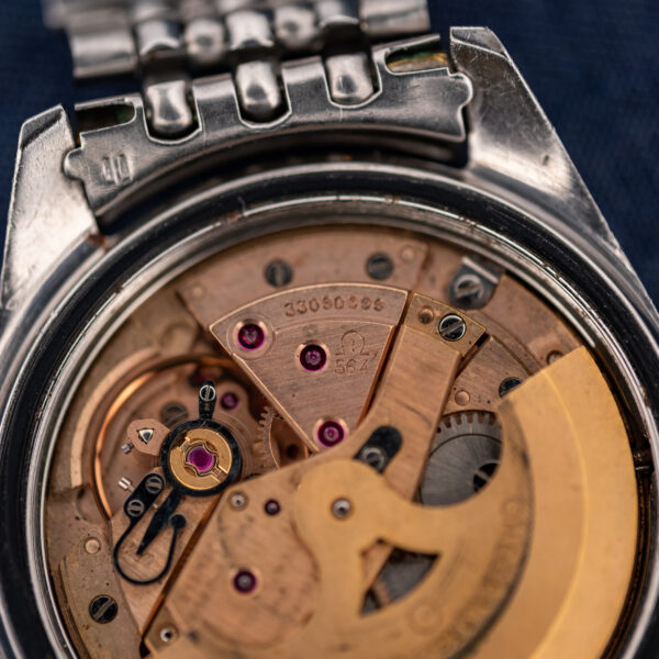 Omega caliber 564 bridge close-up showing stamped caliber, serial number and visible jewels beside the rotor