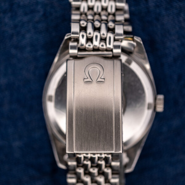 Omega Seamaster bracelet clasp close-up with raised Omega emblem and multirow links above the caseback
