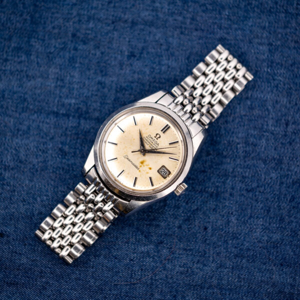 Omega Seamaster 166.010 distant overhead portrait with complete stainless steel bracelet arranged diagonally on blue cloth