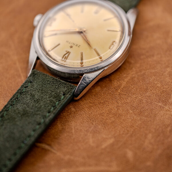 Zenith upper lug close-up showing Arabic twelve, crystal edge and forest green strap joining the case