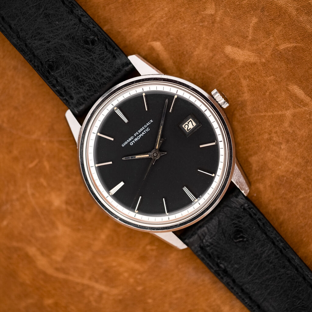 Girard Perregaux Gyromatic overhead view with black dial, white minute ring and textured black strap