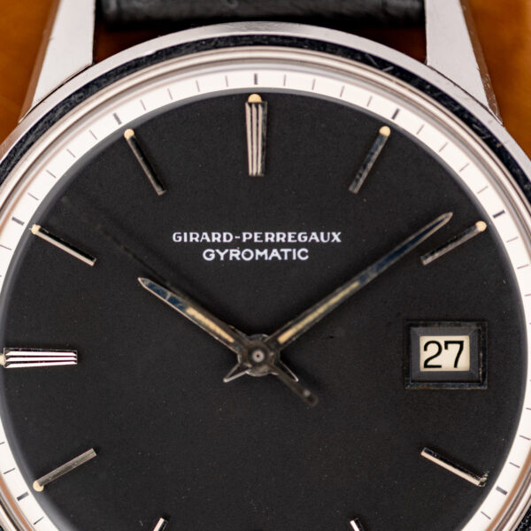 Girard Perregaux Gyromatic dial close-up showing white signature, grooved hour marker and framed date