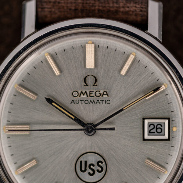 Omega automatic dial close-up showing applied Omega emblem, baton markers and framed date aperture at three