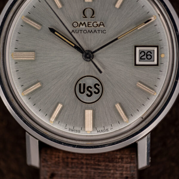 Omega automatic lower dial detail showing circular USS emblem, sunburst texture and Swiss Made marking