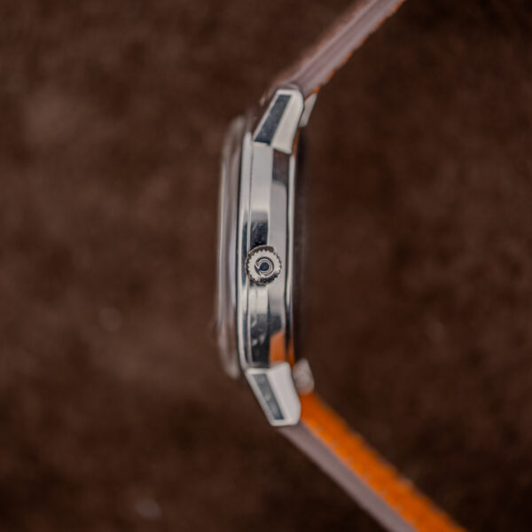 Omega automatic case profile showing signed winding crown, raised crystal edge and strap attached between curved lugs