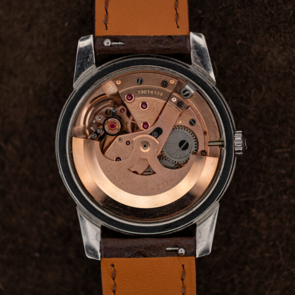 Omega automatic movement in opened Seamaster case, with copper-toned rotor, bridges and winding gears visible