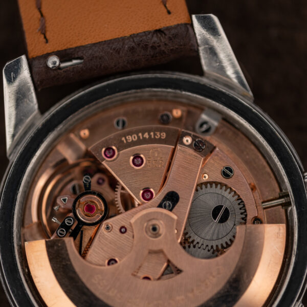 Omega caliber 552 movement detail with stamped bridge, visible jewels and adjacent winding gear under rotor arm