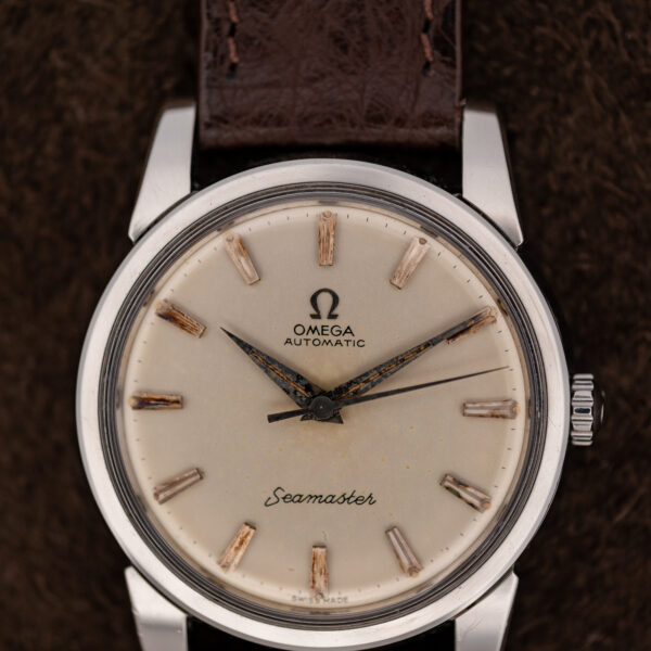 Omega Seamaster dial close-up showing applied Omega emblem, pointed hands and textured baton hour markers