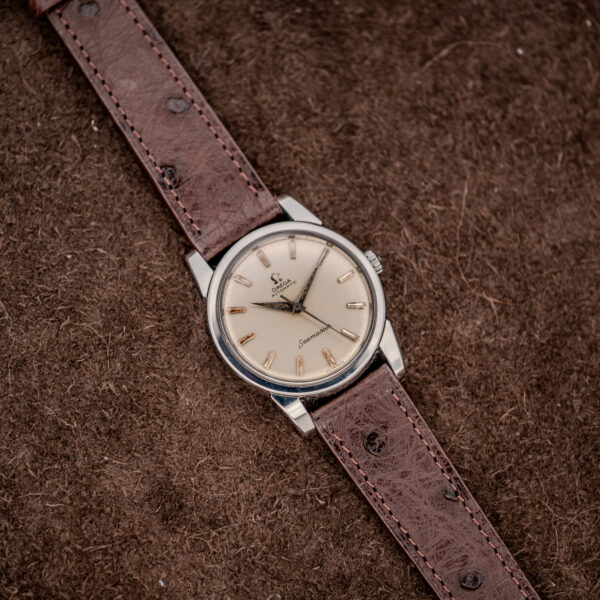 Omega Seamaster 14761 distant overhead view with long choco brown ostrich strap against textured brown background