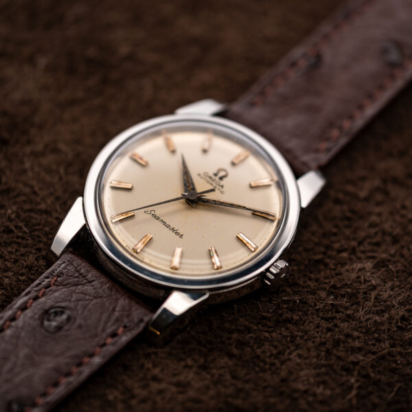 Omega Seamaster crown-side angle showing no-date dial, raised crystal and broad lugs beside ostrich strap