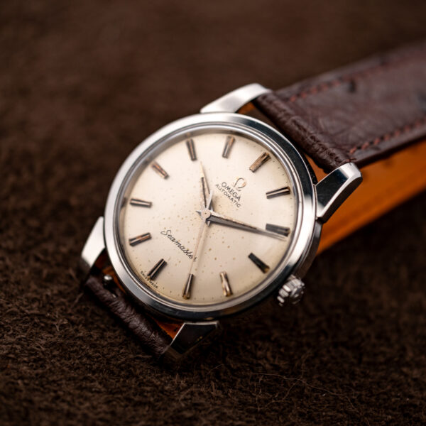 Omega Seamaster oblique dial view with script signature, faceted hour markers and choco brown strap attachment