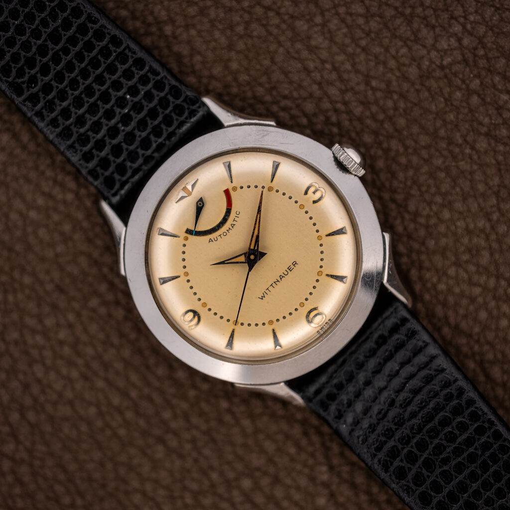 Wittnauer 2092 overhead view with cream dial, curved power reserve indicator and textured black strap