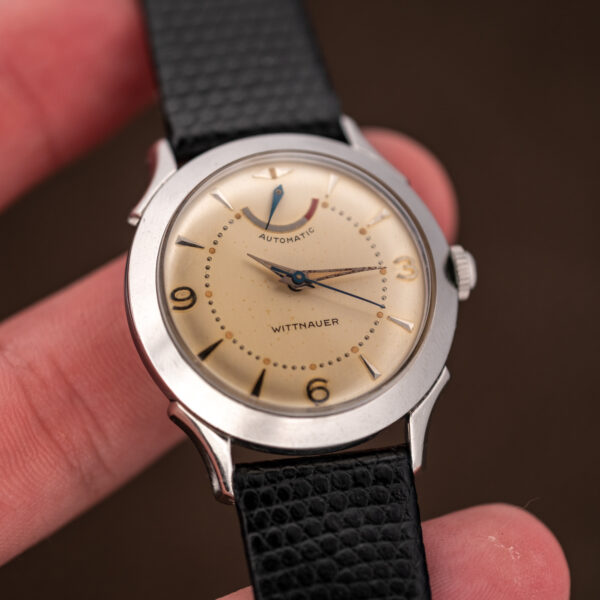 Wittnauer 2092 held in a hand, displaying cream dial and curved power reserve scale