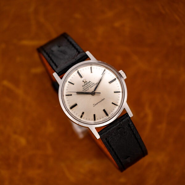 Raised front angle of the Omega Seamaster chronometer with its black ostrich strap looped behind