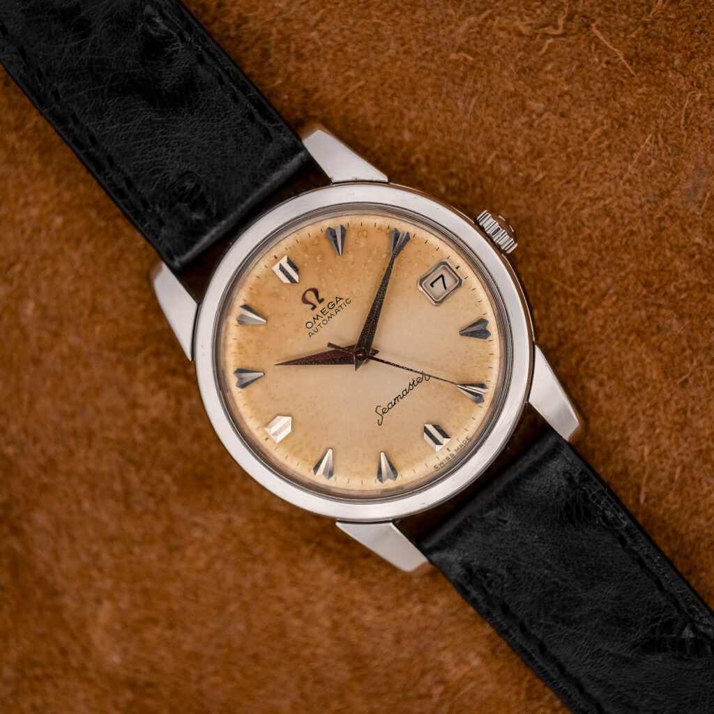 Omega Seamaster 166.009 at an angle, showing the amber-edged tropical dial, faceted silver markers and black strap