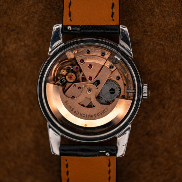 Open caseback of the Omega 166.009 showing the copper-toned caliber 562 movement and signed rotor