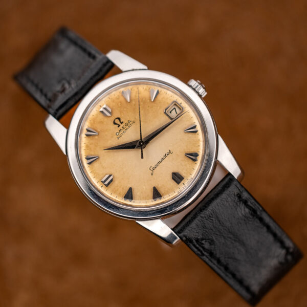 Opposite three-quarter view of the Omega Seamaster amber date dial resting on its black strap