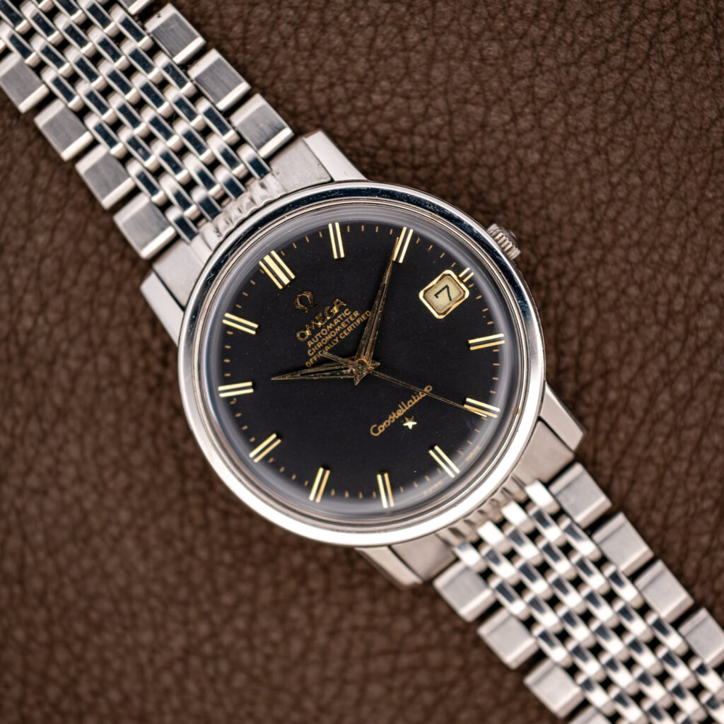 Omega Constellation 168.010 overhead view with black dial, paired hour markers and stainless steel bracelet