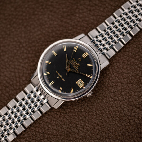 Omega Constellation 168.010 and linked bracelet laid diagonally with black dial and contrasting hour markers
