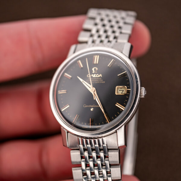 Omega Constellation 168.010 handheld angled view with framed date, paired indices and signed crown