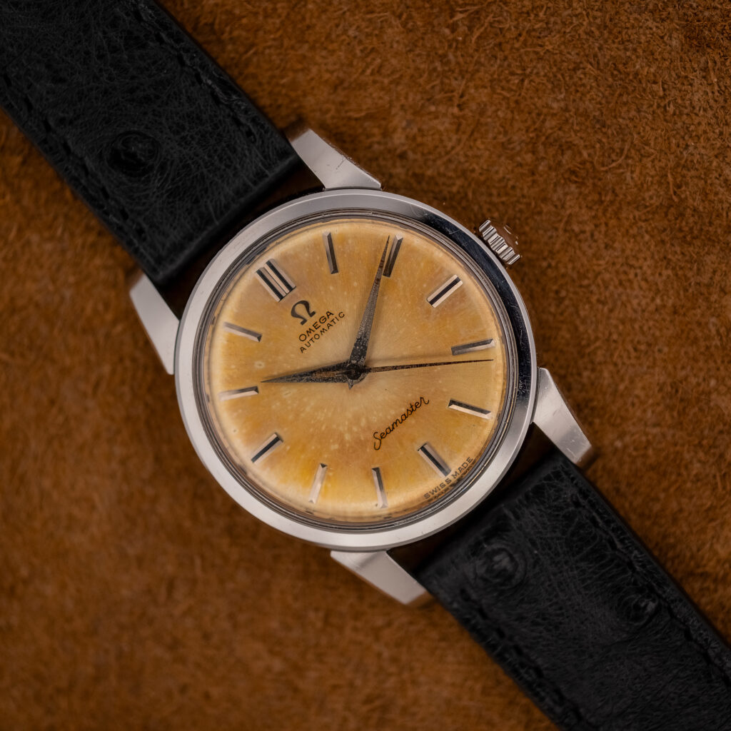 Vintage Omega Seamaster 14761 with amber tropic dial, black-inlaid baton markers and black textured strap, angled front view