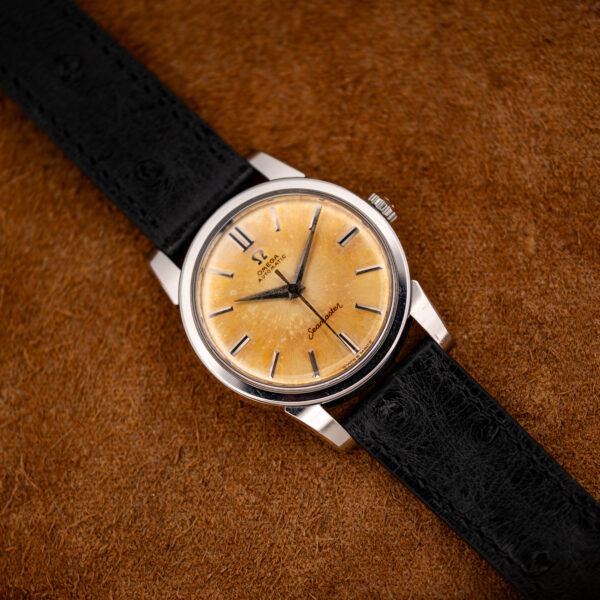 Omega Seamaster 14761 seen from the opposite diagonal, showing the amber dial and silver-tone steel case