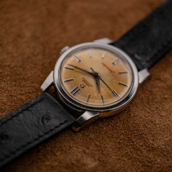 Low oblique angle on the Omega Seamaster showing the domed crystal, amber dial and upper lugs