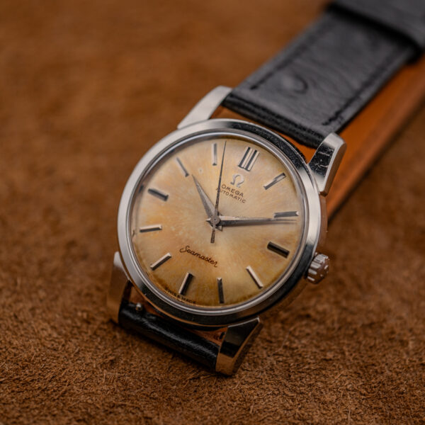 Upright oblique view of the amber Seamaster dial with dark-inlaid hour markers and straight steel lugs