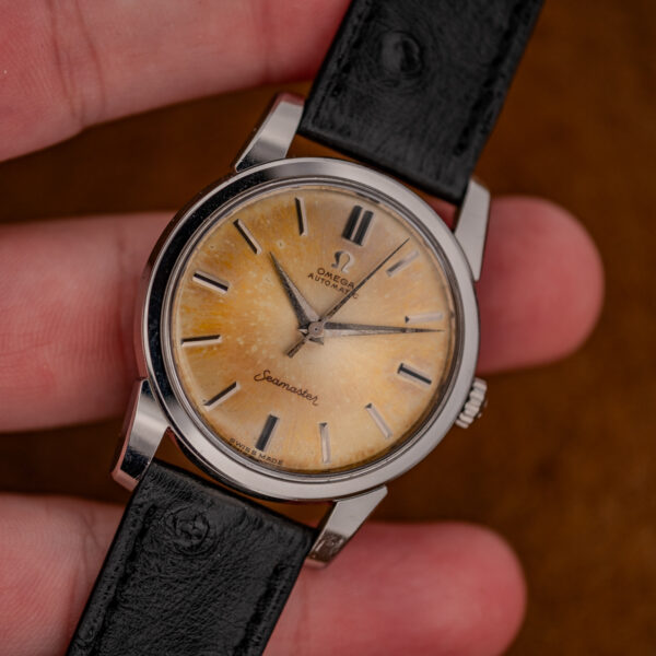 Hand-held Omega Seamaster 14761 showing its amber no-date dial and black textured strap
