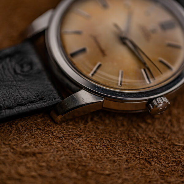 Close view of the Omega Seamaster crown-side lug and bezel edge beside the black textured strap