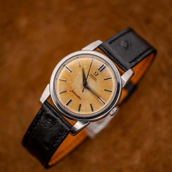 Three-quarter view of the Omega Seamaster with amber dial, its black strap curved into a loop